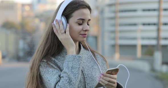 Woman Listening To Music with Headphones in City