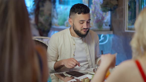 Portrait of Satisfied Handsome Caucasian Young Man Tasting Delicious Food in Restaurant Sitting at