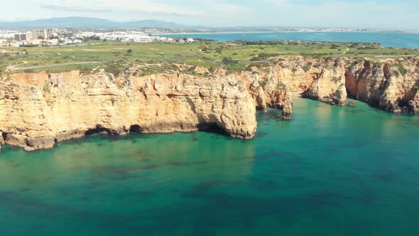 Steep rocky outcrops and calm emerald water in Lagos Algarve, Portugal