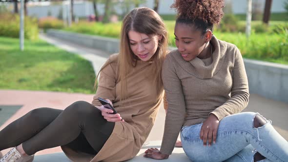 close-up of two girlfriends, black and white young women looking at the phone