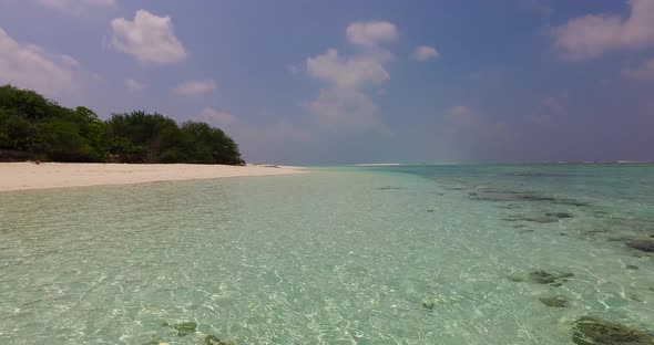 Calm clear water of shallow lagoon with white sand sea bottom, reflecting sunlight of a bright purpl