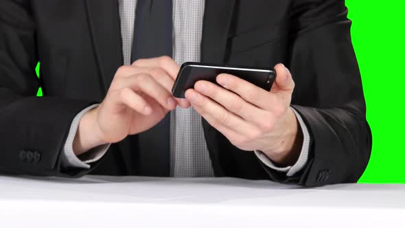 Businessman Sitting at the Table and Uses Phone. Closeup. Green Screen