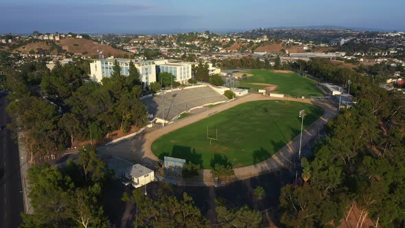 Epic Drone Pullback from a High School on Top of a Hill with a Football Field Revealing Residential