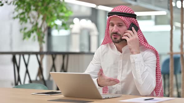 Arab Businessman with Laptop Talking on Smartphone