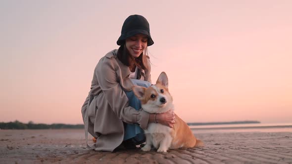 Corgi Dog and Woman in Hat Posing on Beach at Sunset Spbi