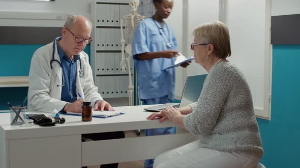 Senior Physician Taking Examination Notes on Checkup Files Report