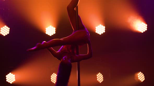 Young Woman Rotates on Pole Performs Split Demonstrating Stretching and Flexibility of Her Body