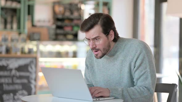 Young Man Reacting to Loss While on Laptop