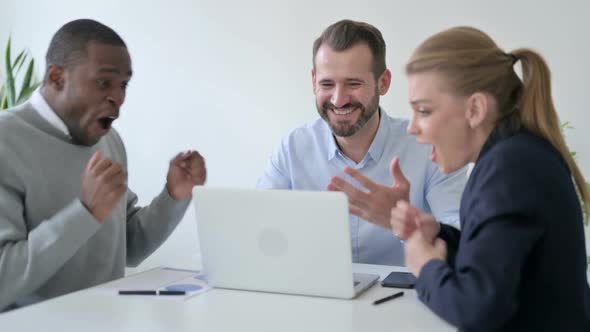 Cheerful Business People Celebrating Success While Using Laptop in Office