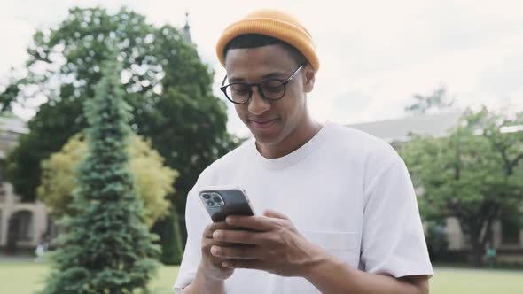 Portrait of an Attractive Young African American Male Student Texting Holding His Phone