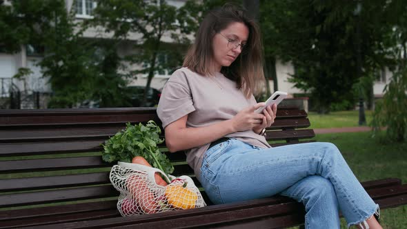 Woman with smartphone and string shopping bag