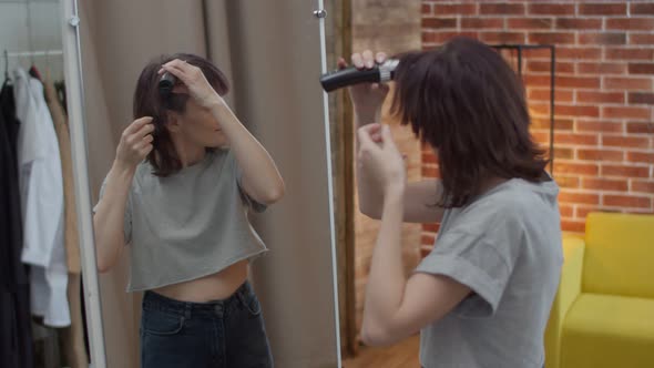 Positive Emotional Woman Shaves a Lock of Hair with a Clipper at the Mirror