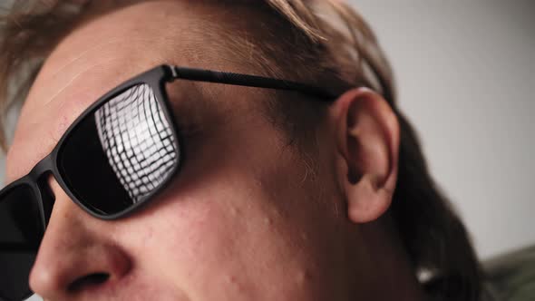 Reflection of the Lighting Fixture in the Black Glasses of a Man