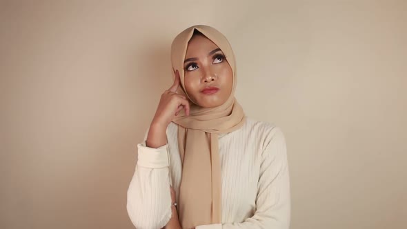 Cheerful young Muslim Asian woman pointing to copy space