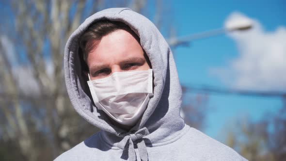 Guy in a medical mask and hood looking straight at the camera. COVID-19 or coronavirus 2019 concept