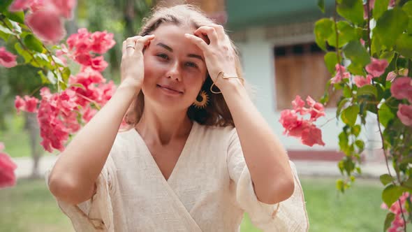 Young Cheerful Caucasian Woman Standing in the Flower Garden