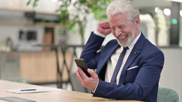 Senior Old Businessman Celebrating Success on Smartphone