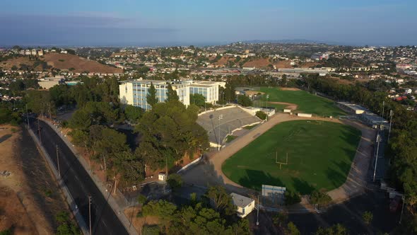 Epic Aerial Pullback from a High School on Top of a Hill with a Football Field Revealing Residential