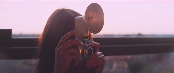 Woman photographer taking a picture on the balcony during golden hour