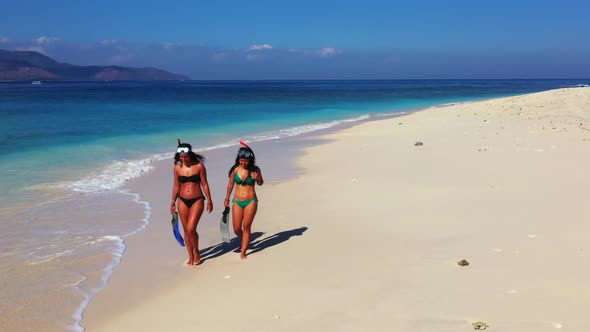 Women enjoying life on tropical coast beach trip by blue sea with white sand background of Gili Meno