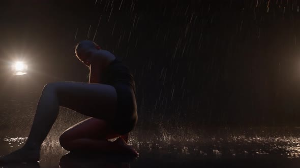 Sensual Young Woman Dancer Performing in the Rain in Dark Studio