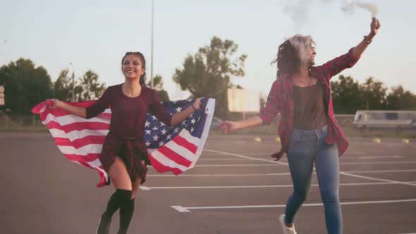 Young Happy American Hipster Girls Running While Holding the American Flag and Letting Off Smoke