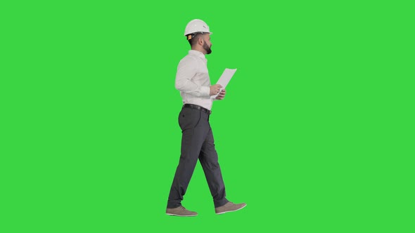 Male Site Contractor Engineer with Hard Hat Walking, Looking at Object and Into Papers, Documents