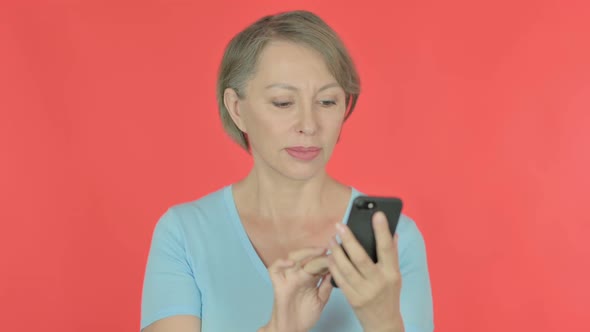 Old Woman Browsing Smartphone on Red Background