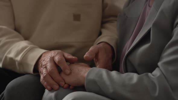 Closeup of the Hands of Elderly Loving Grandparents Clasped Together on Their Laps