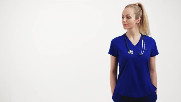 Medium Shot of Nurse in a Blue Uniform Keeping Her Hands in Pockets and Turning Her Head to the Side