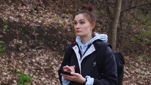 Woman with a Backpack Looking the Route on the Maps on the Phone in the Forest