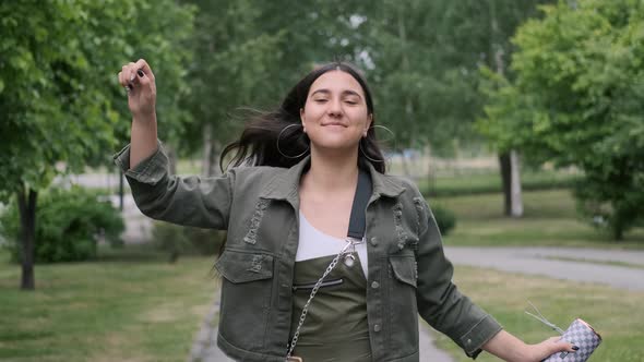 Hipster Girl in Good Mood Walks Down the Street and Listens To Music Using a Portable Speaker