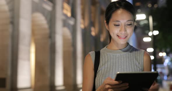 Woman use of tablet computer in city at night 