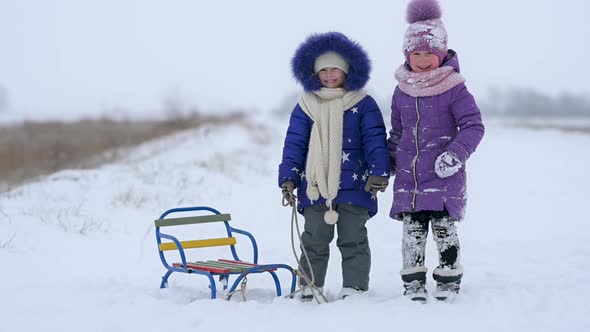 Healthy kids with sledges look at the camera