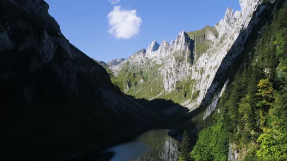 aerial drone flight through mountain valley with reflecting lake in switzerland