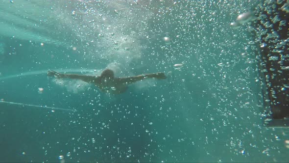 Bubbles Underwater and Man in Red Short Swimming