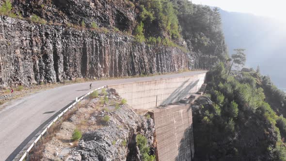 Professional cyclist riding bicycle on asphalt road in mountains