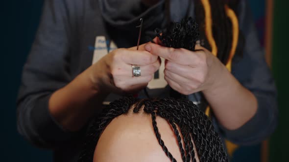 Unrecognizable Person Makes Hairstyle for Young Woman in Salon