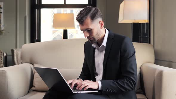 Focused Businessman Working on Laptop Computer at Lobby Hotel