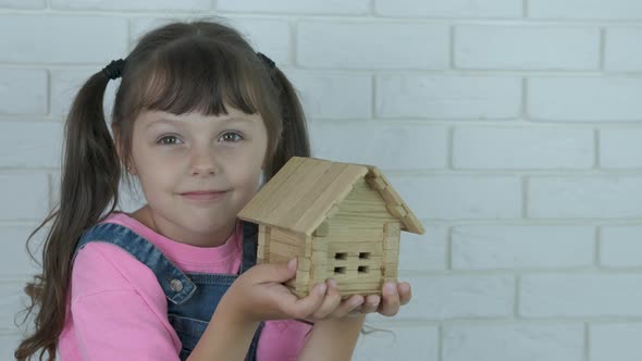 Child with a wooden house toy.