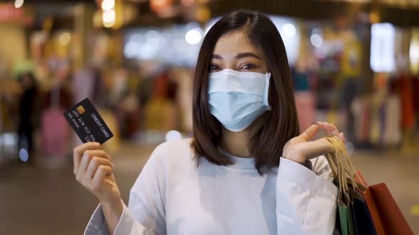 woman wearing medical mask and holding credit card at shopping mall for prevention from coronavirus