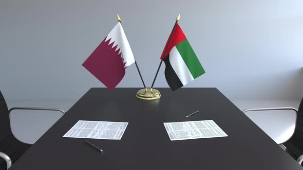 Flags of Qatar and the UAE and Papers on the Table alt