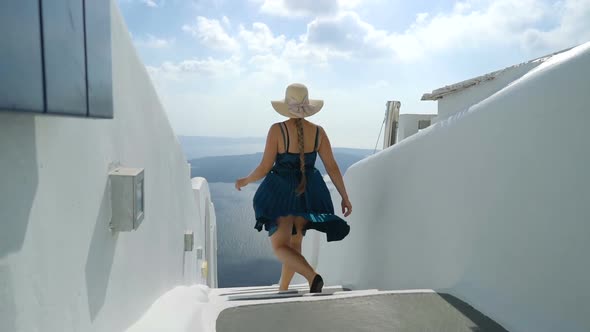 Happy Woman in Green Dress and Sun Hat Enjoying Her Holidays on Santorini, Greece. View on Caldera