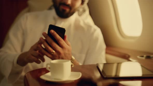 Happy Arabian Swiping Smartphone on Business Trip