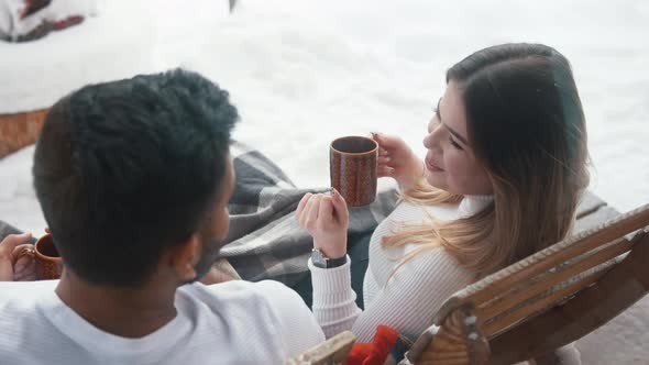 Happy Young Couple Drinking Hot Chocolate While Sitting on the Bench Outdoors on Valentines Day