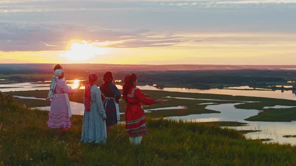 Young People in Russian Traditional Clothes Standing on the Field and Enjoying the View on Sunset