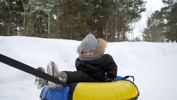 Happy Parents are Running and Sliding Their Son in Tubing in Winter Park