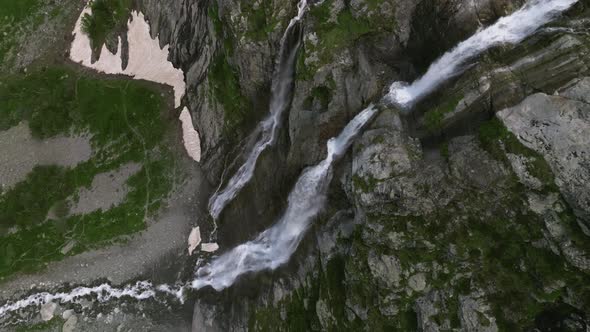 Aerial View Close Up Flight with Mountain Waterfalls Flowing From Glacier Over Rocks