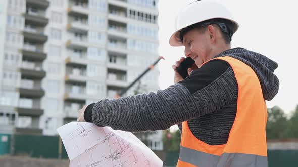 Construction Engineer Conducts a Telephone Conversation with a Customer at a Construction Site