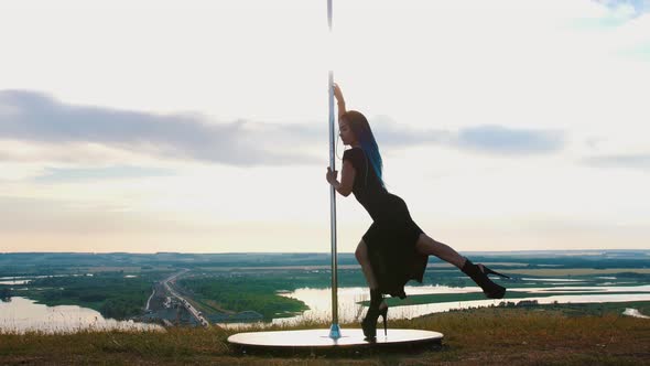 Pole Dance on Nature - Sexy Woman with Long Blue Braids in Black Clothes Dancing on High Heels